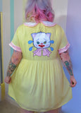 girl wearing yellow dress with pink trimmed sleeves and collar. back image of a crying clown cat